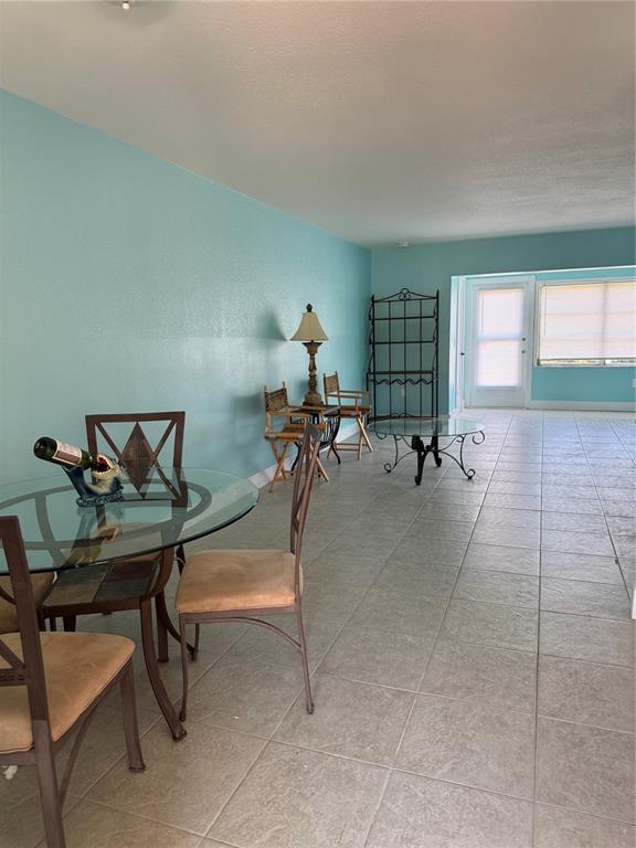 A dining area with a glass table and tile flooring opens into a living space — 4515` MARINE PARKWAY UNIT 102, NEW PORT RICHEY, FL