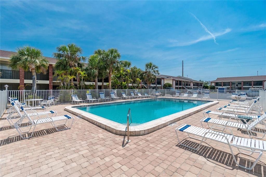 An outdoor swimming pool surrounded by lounge chairs and palm trees at a residential complex — 1531 PLACIDA ROAD UNIT 1-204, ENGLEWOOD, FL