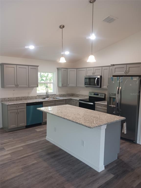 A kitchen features gray cabinets, granite countertops, stainless steel appliances, and a central island — 57 PINE TRACE RUN, OCALA, FL