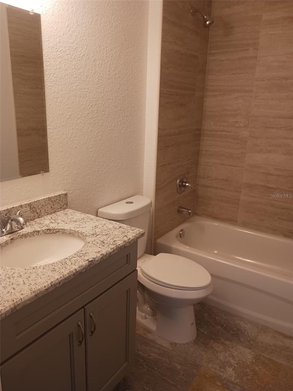 A bathroom features a granite-topped vanity, a white toilet, and a tiled shower-tub combination — 57 PINE TRACE RUN, OCALA, FL
