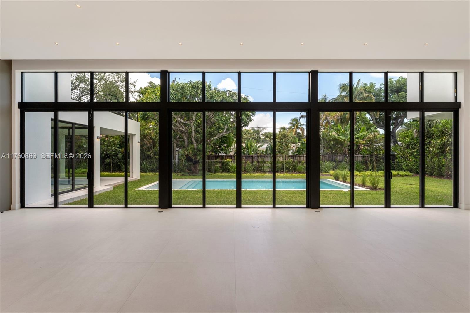 A modern kitchen features a marble waterfall island, light wood cabinetry, and integrated appliances — 5921 SW 84th St, South Miami FL 33143, SOUTH MIAMI, FL