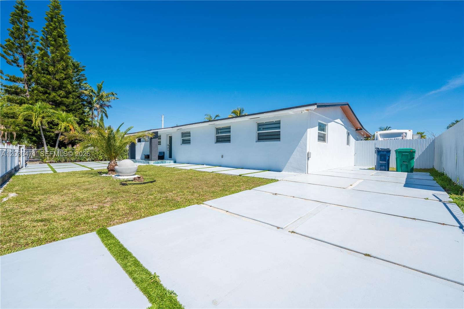 A white, single-story house features a paved driveway and a small lawn with palm trees — 11851 SW 181st St, Miami FL 33177, MIAMI, FL
