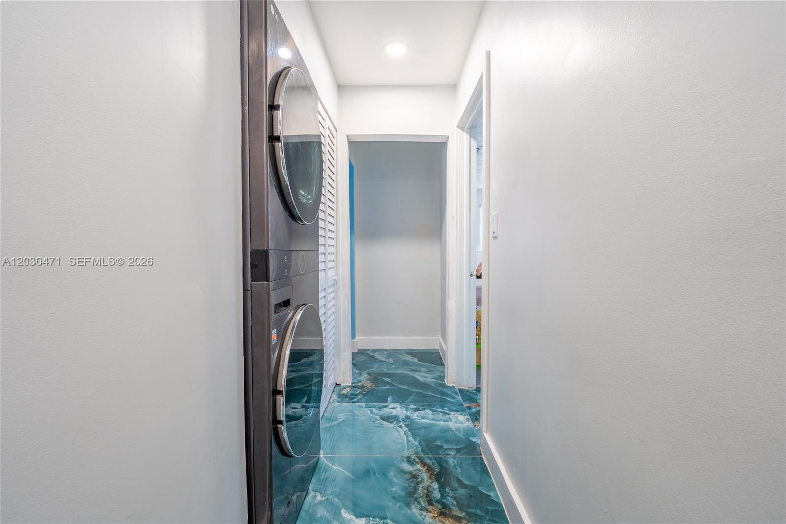A narrow hallway features a stacked washer and dryer and blue marble-patterned tile flooring — 11851 SW 181st St, Miami FL 33177, MIAMI, FL