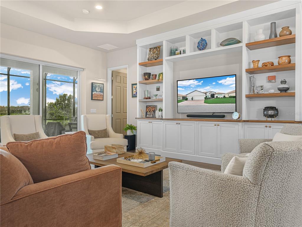 A living room features built-in white shelving, a television, and neutral-toned furniture — 6209 PINEHURST LOOP, WINTER HAVEN, FL