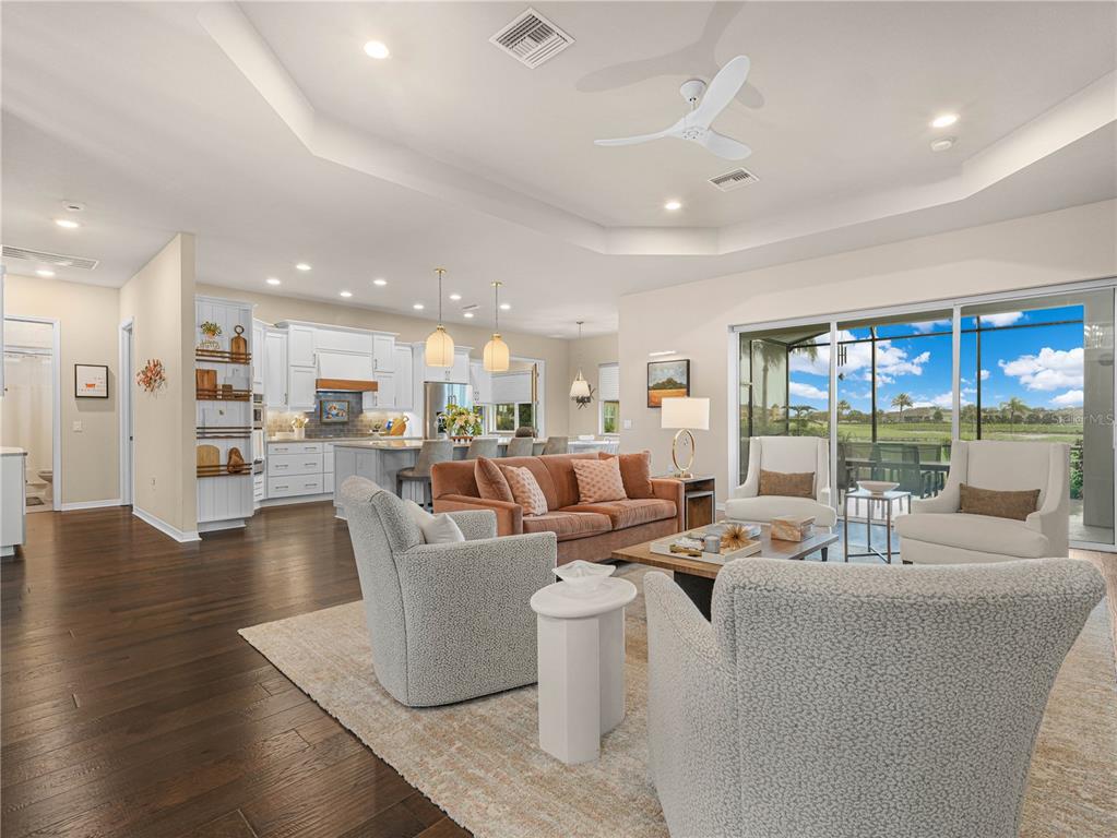 An open-concept living room with hardwood floors, a sofa, armchairs, and a view of a patio — 6209 PINEHURST LOOP, WINTER HAVEN, FL