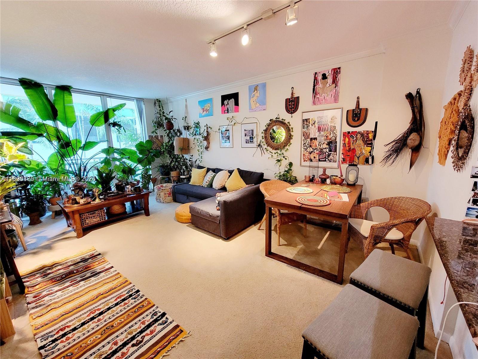 A living and dining area features a sofa, wooden table, wicker chairs, and many houseplants — 2000 N Bayshore Dr # 226, Miami FL 33137, MIAMI, FL