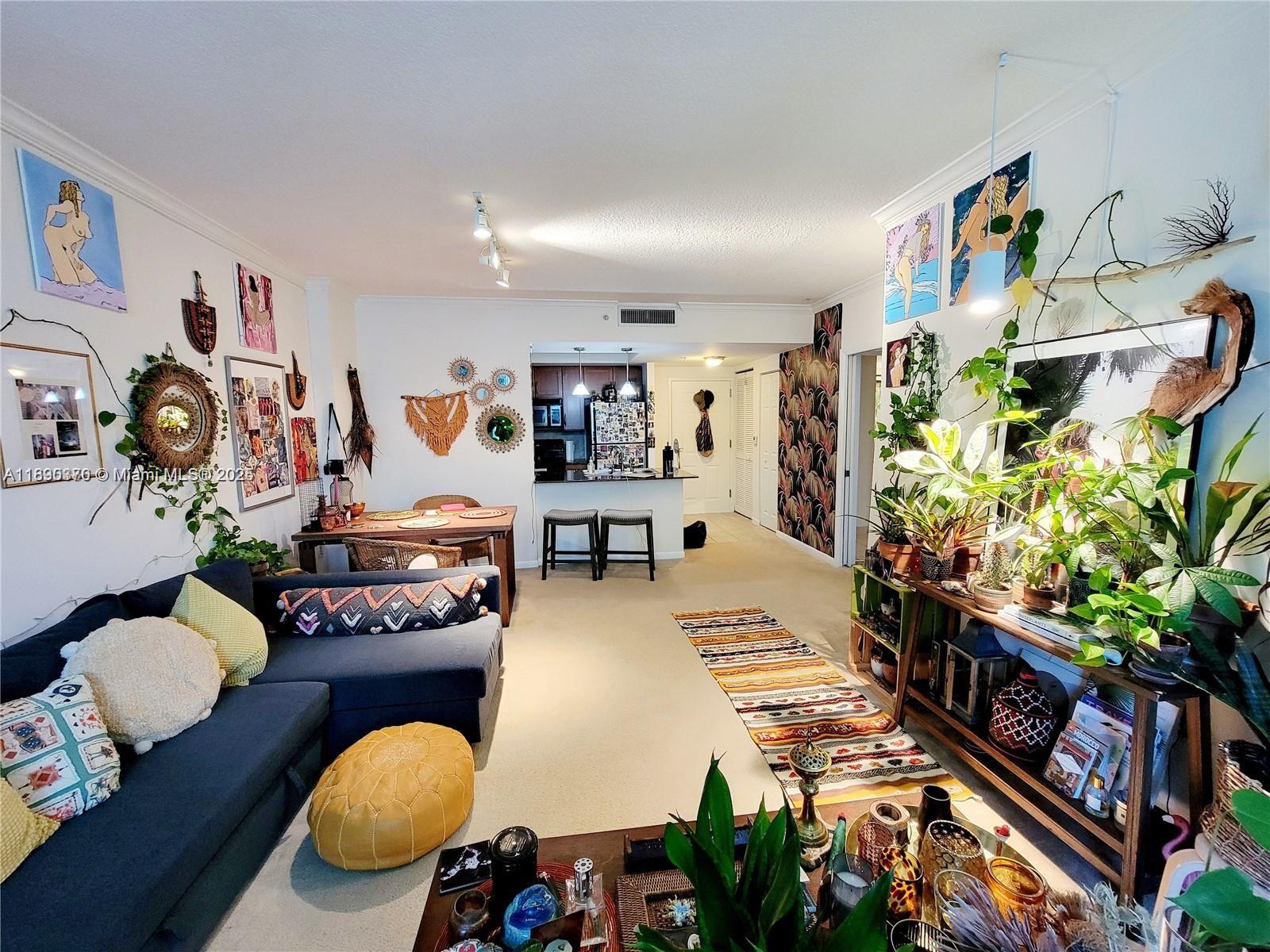 A living room with a dark sofa, dining area, kitchen, and many indoor plants — 2000 N Bayshore Dr # 226, Miami FL 33137, MIAMI, FL