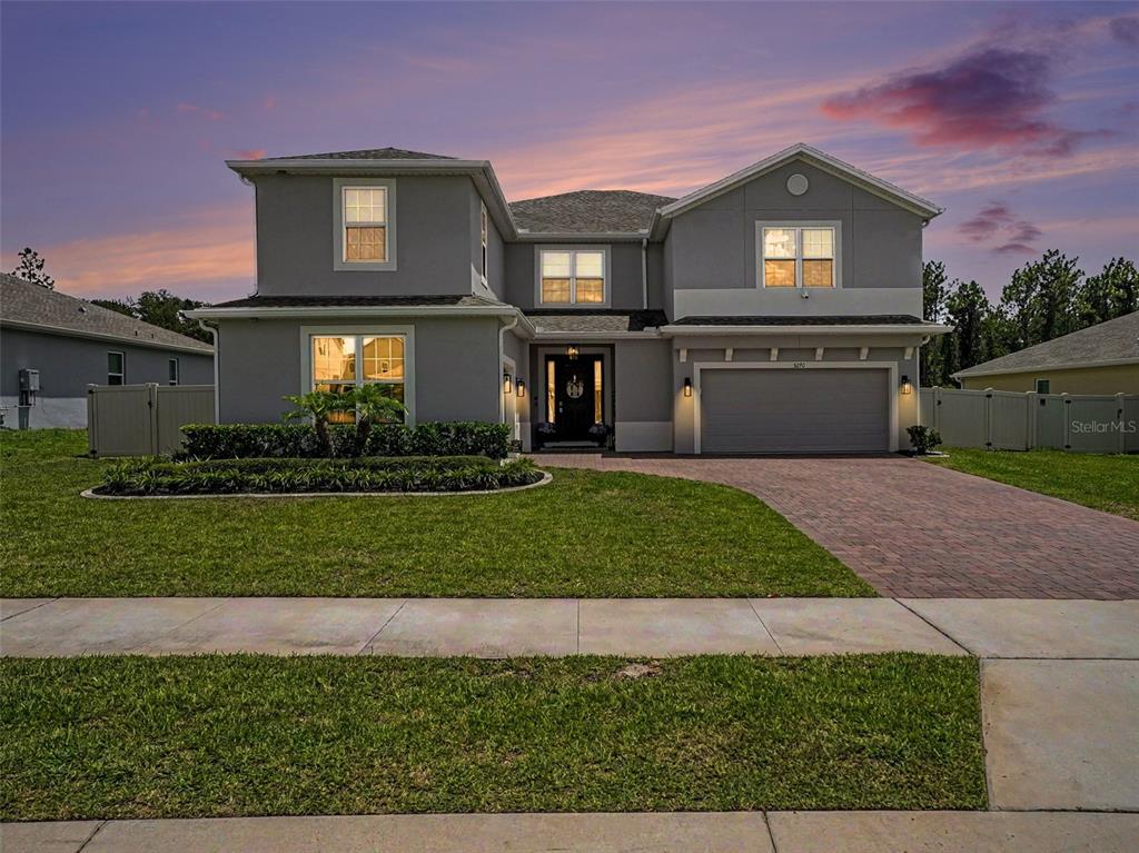 A two-story gray house with a two-car garage and a paved driveway at sunset — 5270 OBSIDIAN GATE DRIVE, MOUNT DORA, FL