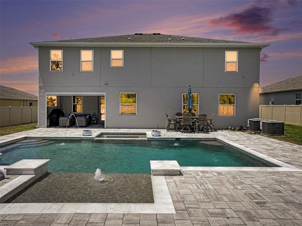 A two-story house exterior features a backyard swimming pool with a fountain and patio — 5270 OBSIDIAN GATE DRIVE, MOUNT DORA, FL