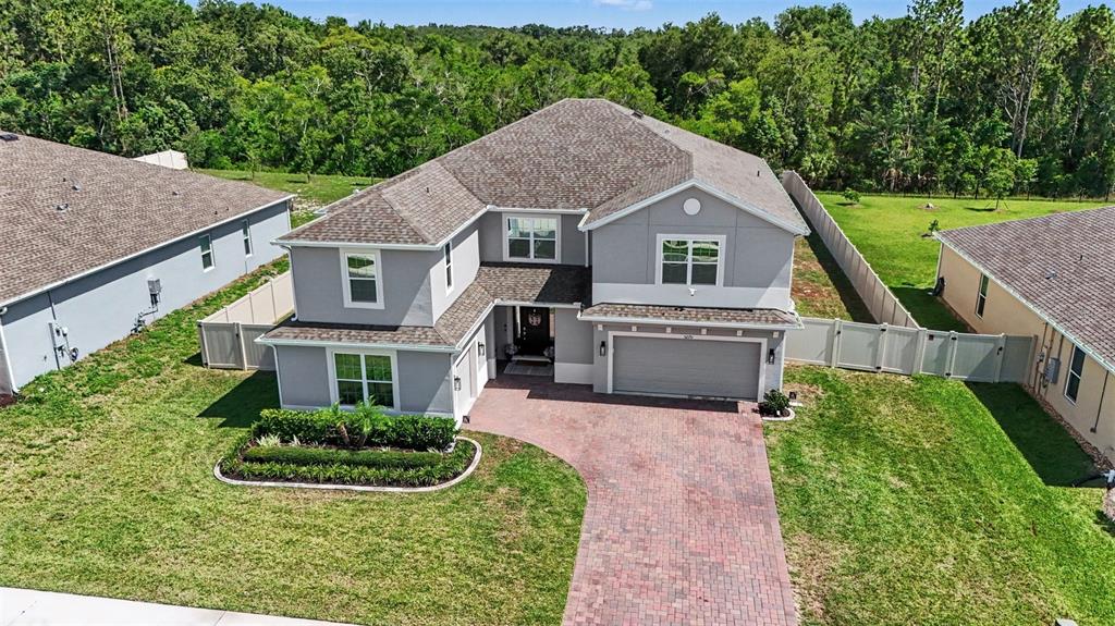 An aerial view of a two-story gray house with a brick driveway and fenced yard — 5270 OBSIDIAN GATE DRIVE, MOUNT DORA, FL