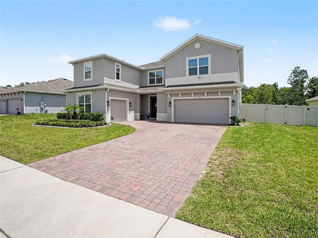 A two-story gray house with a brick paver driveway and a three-car garage — 5270 OBSIDIAN GATE DRIVE, MOUNT DORA, FL
