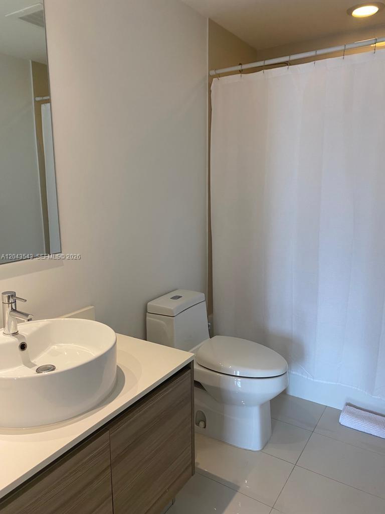 A bathroom features a vessel sink vanity, a toilet, and a shower with a white curtain — 121 NE 34th St # 1703, Miami FL 33137, MIAMI, FL