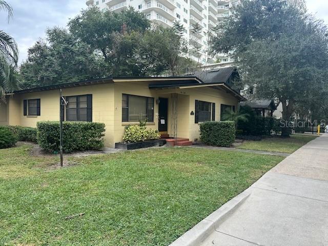 A yellow, single-story house with a flat roof sits next to a tall apartment building — 501 E CHURCH STREET, ORLANDO, FL