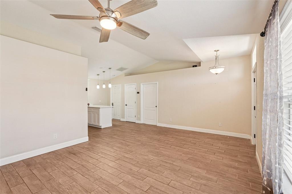An open-concept living area features light wood-look tile flooring, a ceiling fan, and a kitchen — 1929 NORVELL AVENUE, NORTH PORT, FL