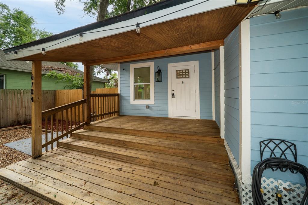 A wooden porch with steps leads to a blue house with a white front door — 6704 N TALIAFERRO AVENUE, TAMPA, FL
