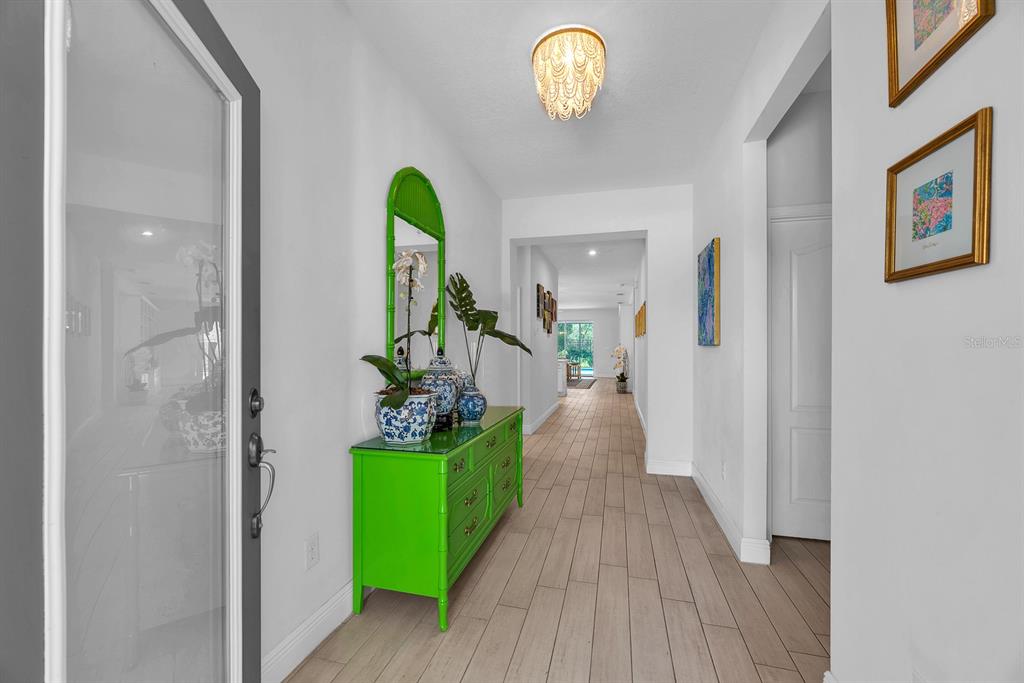A bright entryway features a lime green chest, a decorative mirror, and light wood flooring — 14115 CARISSA MEADOWS COURT, RIVERVIEW, FL