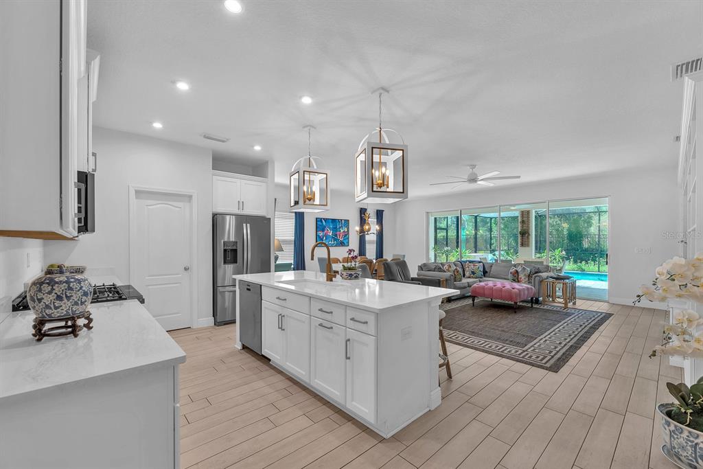 A bright open-concept kitchen features a white island, stainless steel appliances, and a living area — 14115 CARISSA MEADOWS COURT, RIVERVIEW, FL