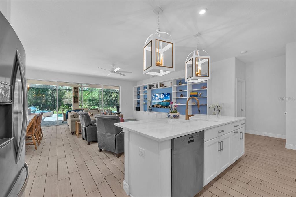 A kitchen island with a sink faces a living area featuring built-in blue shelving — 14115 CARISSA MEADOWS COURT, RIVERVIEW, FL