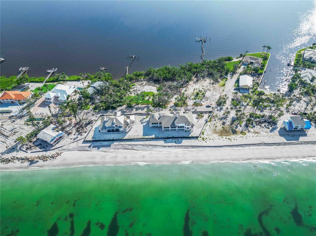 An aerial view shows beachfront houses with docks extending into the water along the coast — 6845 MANASOTA KEY ROAD, ENGLEWOOD, FL