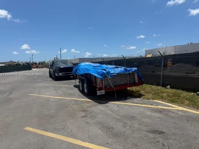 A dark pickup truck tows a trailer covered by a blue tarp in a parking lot — 7500 NW 74th Ave, Medley FL 33166, MEDLEY, FL