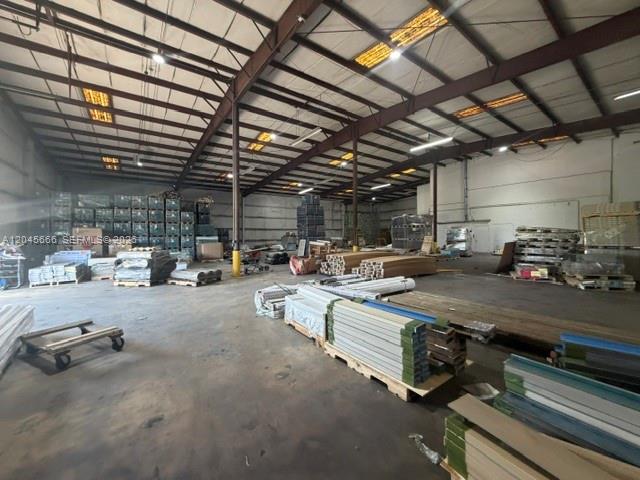 This industrial warehouse space features high ceilings, exposed steel beams, and various stored materials — 7500 NW 74th Ave, Medley FL 33166, MEDLEY, FL