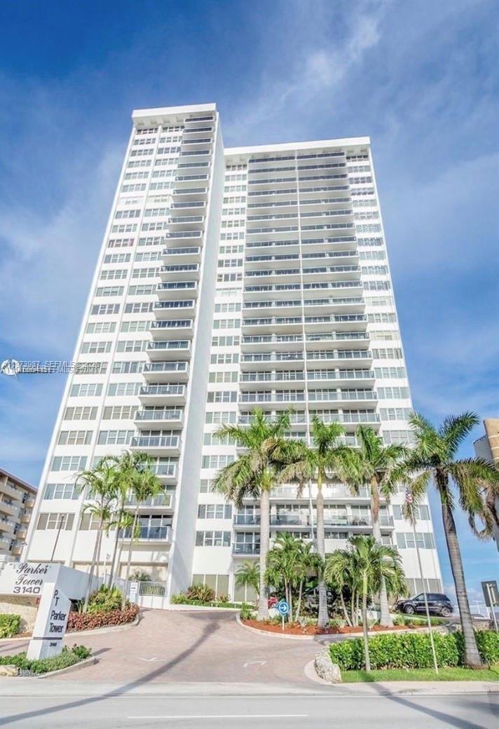 A tall white residential high-rise building stands behind a paved driveway and palm trees — 3140 S Ocean Dr # 1812, Hallandale Beach FL 33009, HALLANDALE BEACH, FL