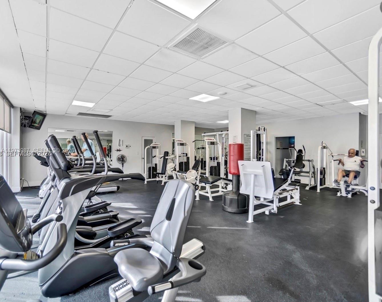 A gym room features multiple exercise machines, a red punching bag, and a drop ceiling — 3140 S Ocean Dr # 1812, Hallandale Beach FL 33009, HALLANDALE BEACH, FL