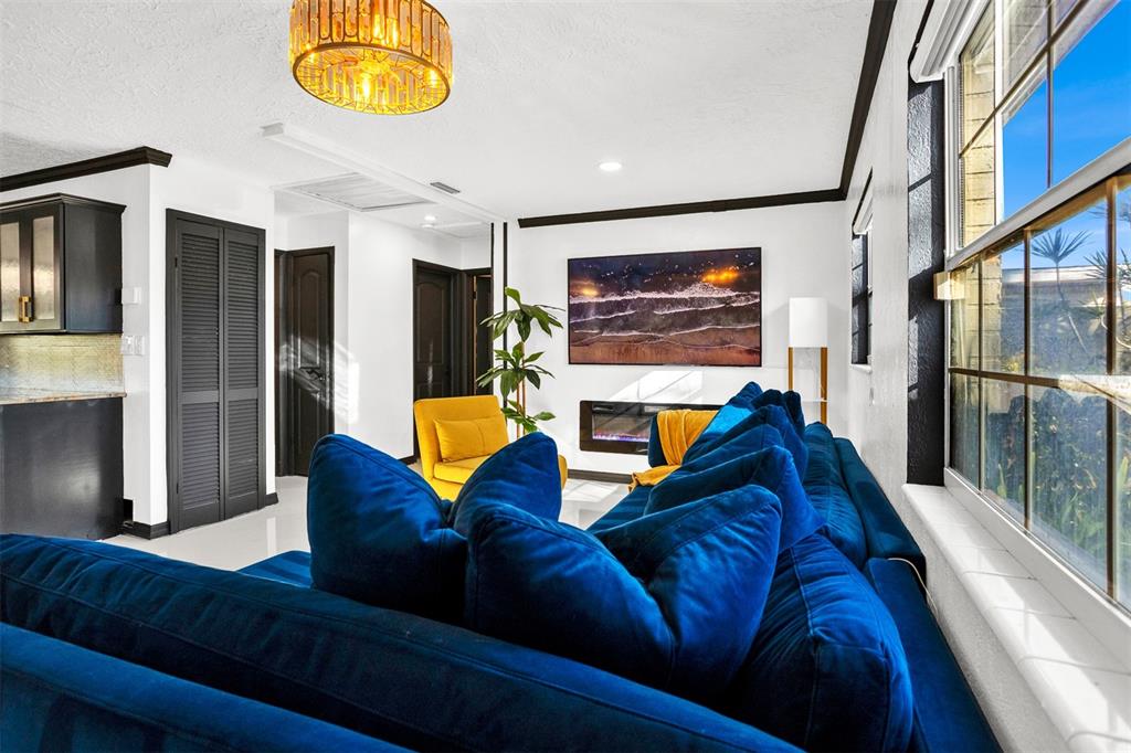 A living room features a large blue sectional sofa, a fireplace, and a yellow armchair — 5564 N 63RD WAY N, ST PETERSBURG, FL