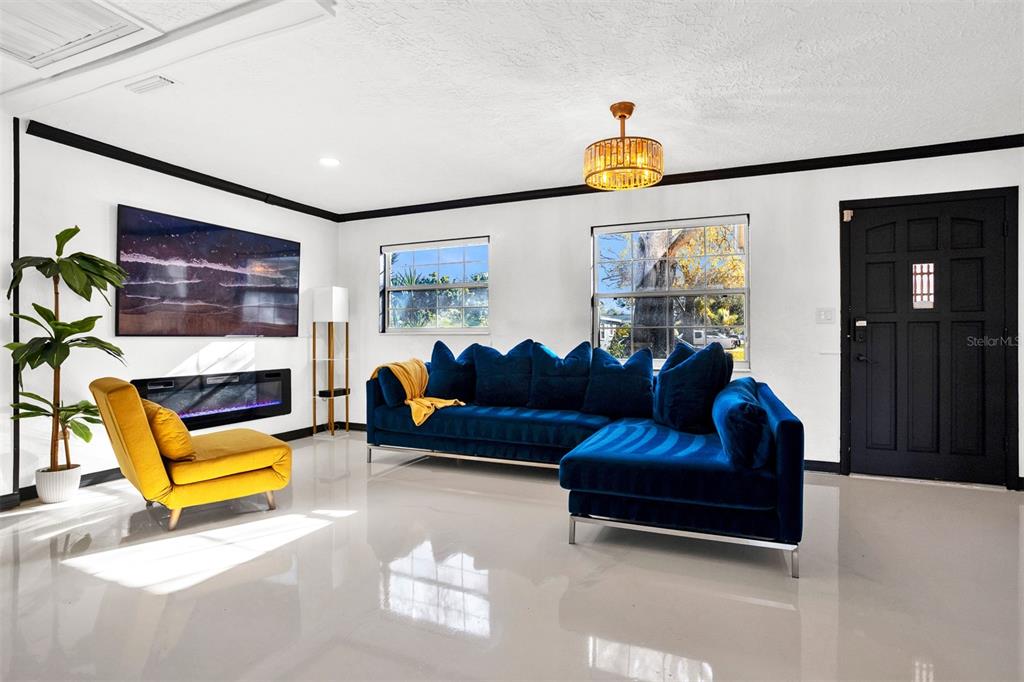 A living room features a blue sectional sofa, a yellow chair, and a wall-mounted fireplace — 5564 N 63RD WAY N, ST PETERSBURG, FL