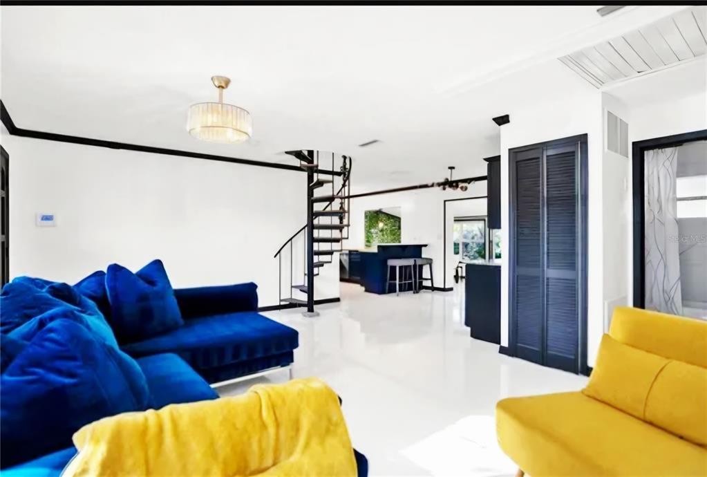 A living room with a spiral staircase, white tile floors, and blue and yellow furniture — 5564 N 63RD WAY N, ST PETERSBURG, FL