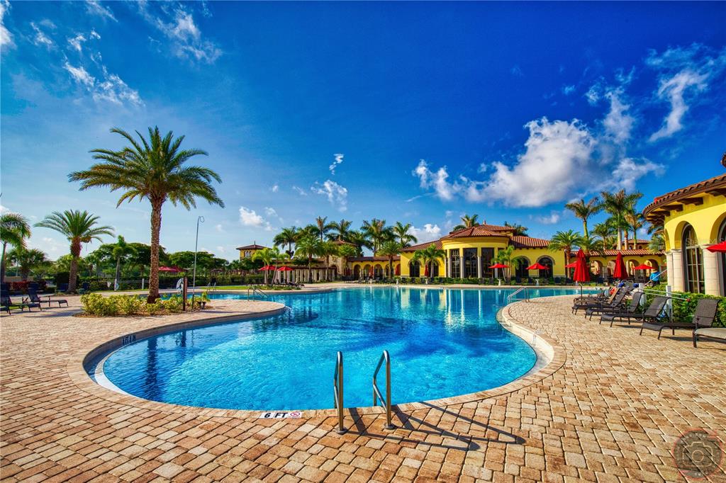 A large swimming pool with a brick deck and palm trees in front of a clubhouse — 12355 GHIBERTI CIRCLE UNIT 101, VENICE, FL
