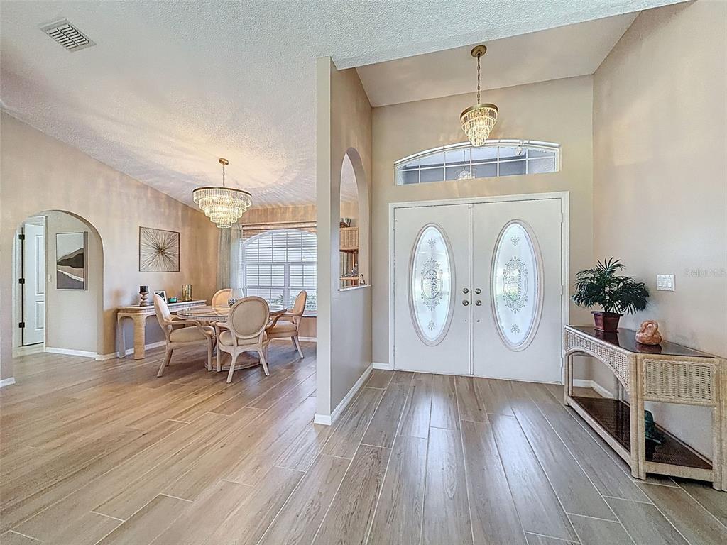 An entryway with wood-look tile floors leads to a dining room with a crystal chandelier — 9428 APPLE DUMPLING COURT, WEEKI WACHEE, FL