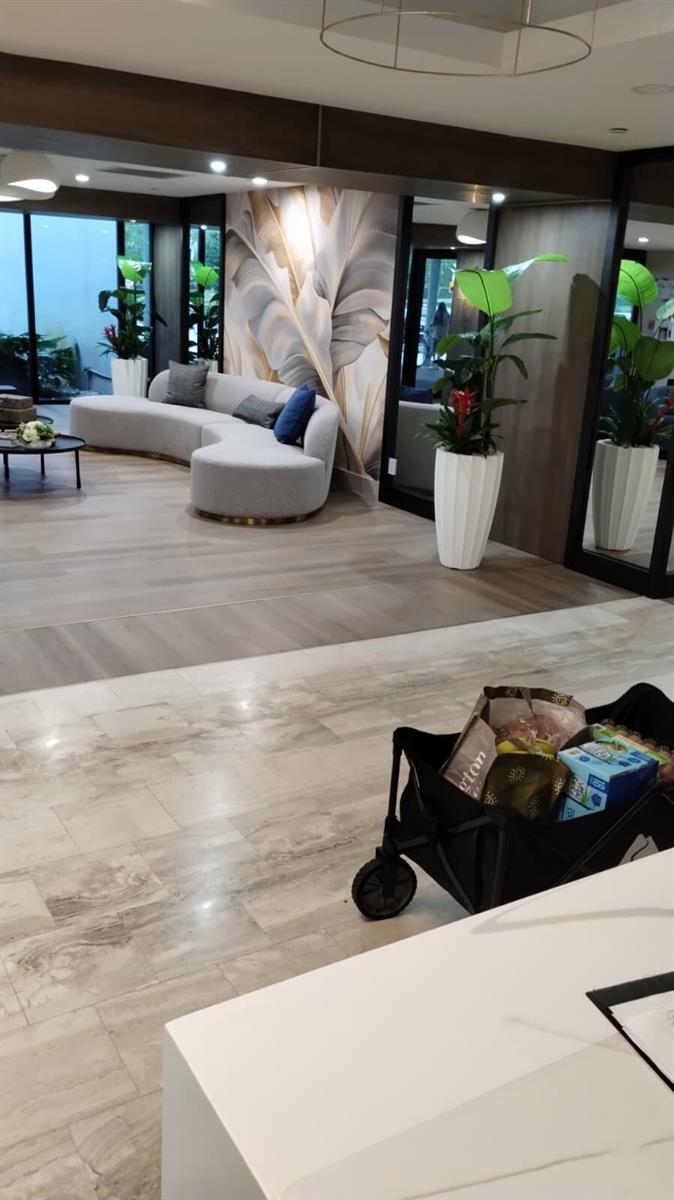 A modern lobby features a curved gray sofa, large potted plants, and a grocery cart — 4200 Hillcrest Drive # 707, Hollywood FL 33021, HOLLYWOOD, FL