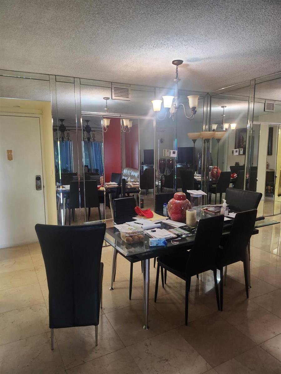 A dining room features a glass-topped table, black chairs, and mirrored wall panels — 4200 Hillcrest Drive # 707, Hollywood FL 33021, HOLLYWOOD, FL