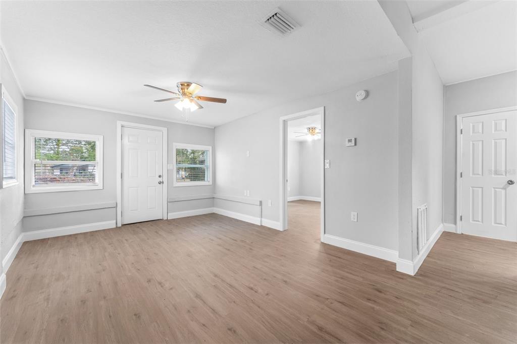 A living room with light gray walls, wood-look flooring, a ceiling fan, and two doors — 1927 13TH STREET S, ST PETERSBURG, FL