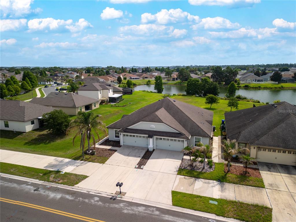 An aerial view of a suburban duplex home with a shared driveway and pond view — 5581 MAGGIORE BOULEVARD, LAKELAND, FL
