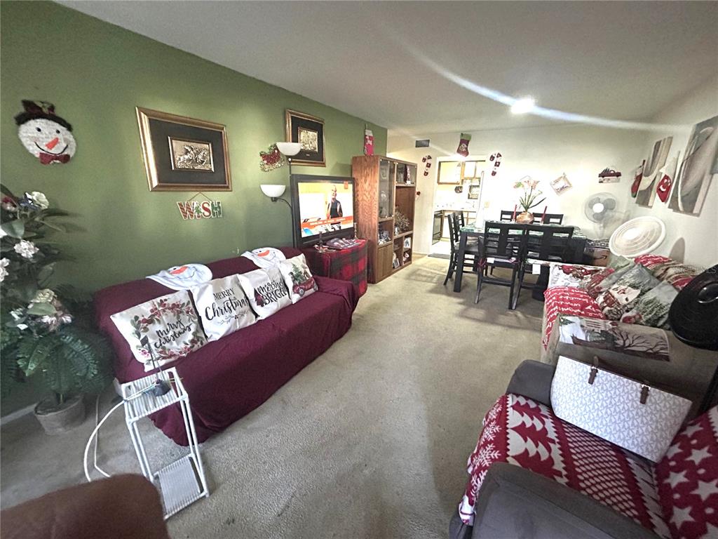 A living room with a green wall, a maroon sofa, and an adjacent dining area — 4115 S SEMORAN BOULEVARD UNIT 19, ORLANDO, FL