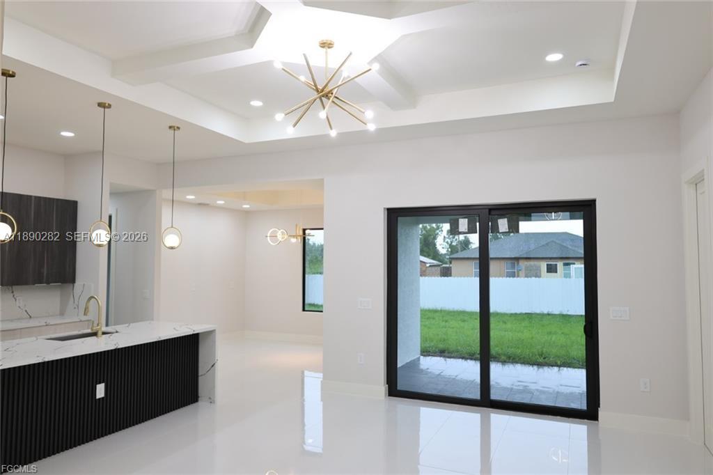 A modern kitchen and living area feature a black island, gold lighting, and sliding doors — 2800 33rd ST SW, Lehigh Acres FL 33976, LEHIGH ACRES, FL