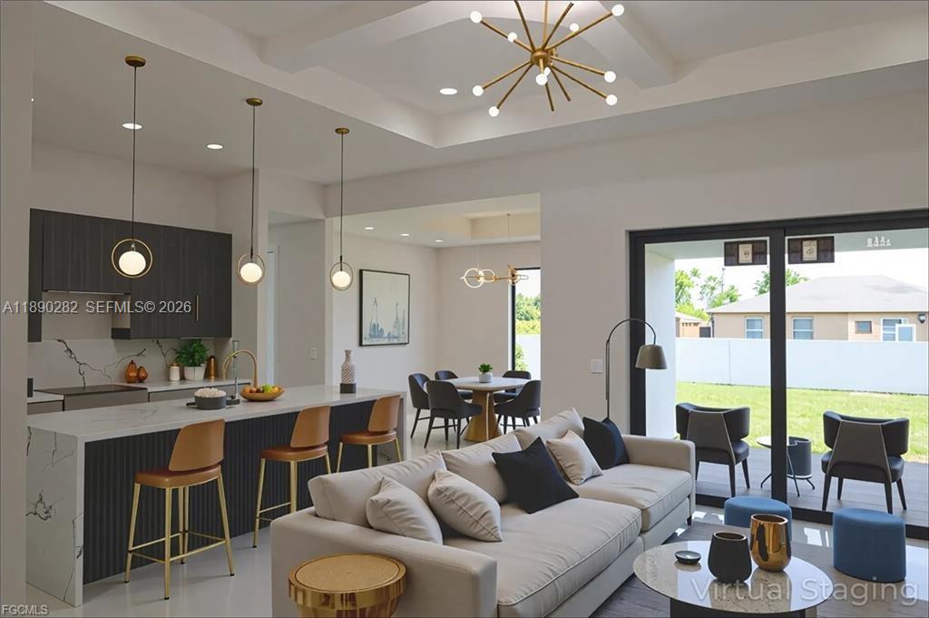 A modern open-concept kitchen and living area features a marble island, pendant lighting, and patio — 2800 33rd ST SW, Lehigh Acres FL 33976, LEHIGH ACRES, FL