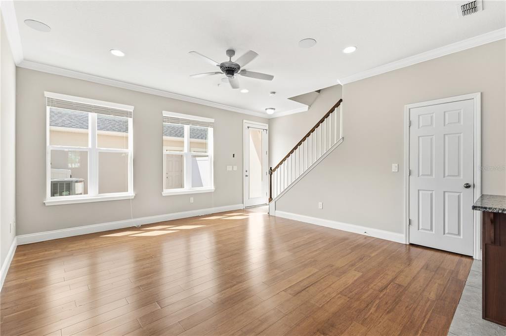 An empty room features light-colored walls, wood flooring, a ceiling fan, and a staircase — 8049 CADMAN STREET, ORLANDO, FL