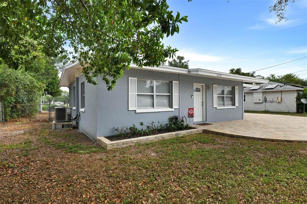 A gray single-story house with a paved front patio and a small garden bed — 1224 BELLEVUE BOULEVARD, CLEARWATER, FL