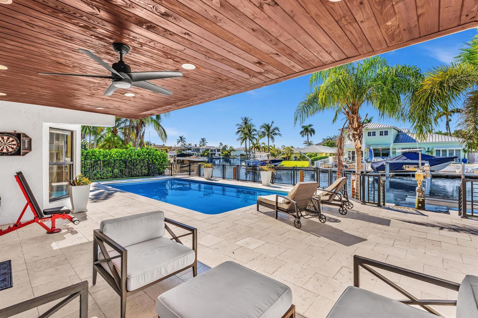 A covered patio features a swimming pool, lounge chairs, and a view of a canal — 2888 NE 33rd Street, Lighthouse Point FL 33064, LIGHTHOUSE POINT, FL
