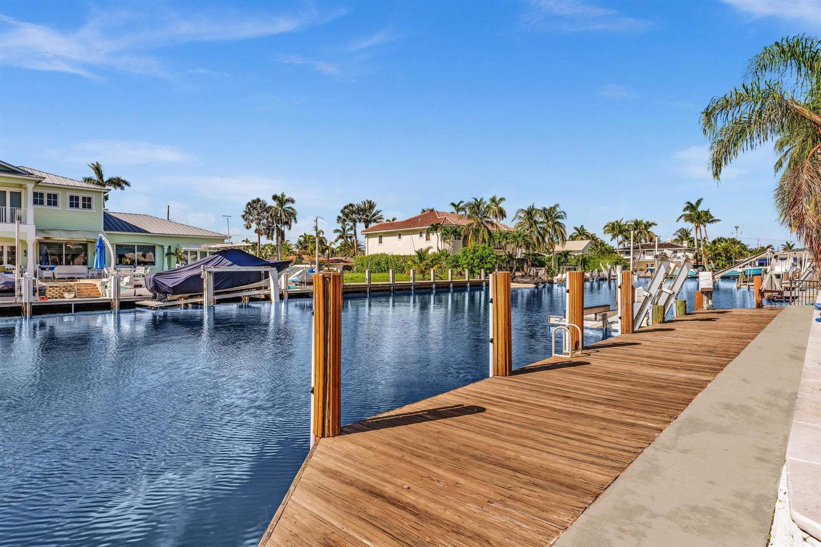 A wooden boat dock extends over a canal lined with houses and palm trees — 2888 NE 33rd Street, Lighthouse Point FL 33064, LIGHTHOUSE POINT, FL