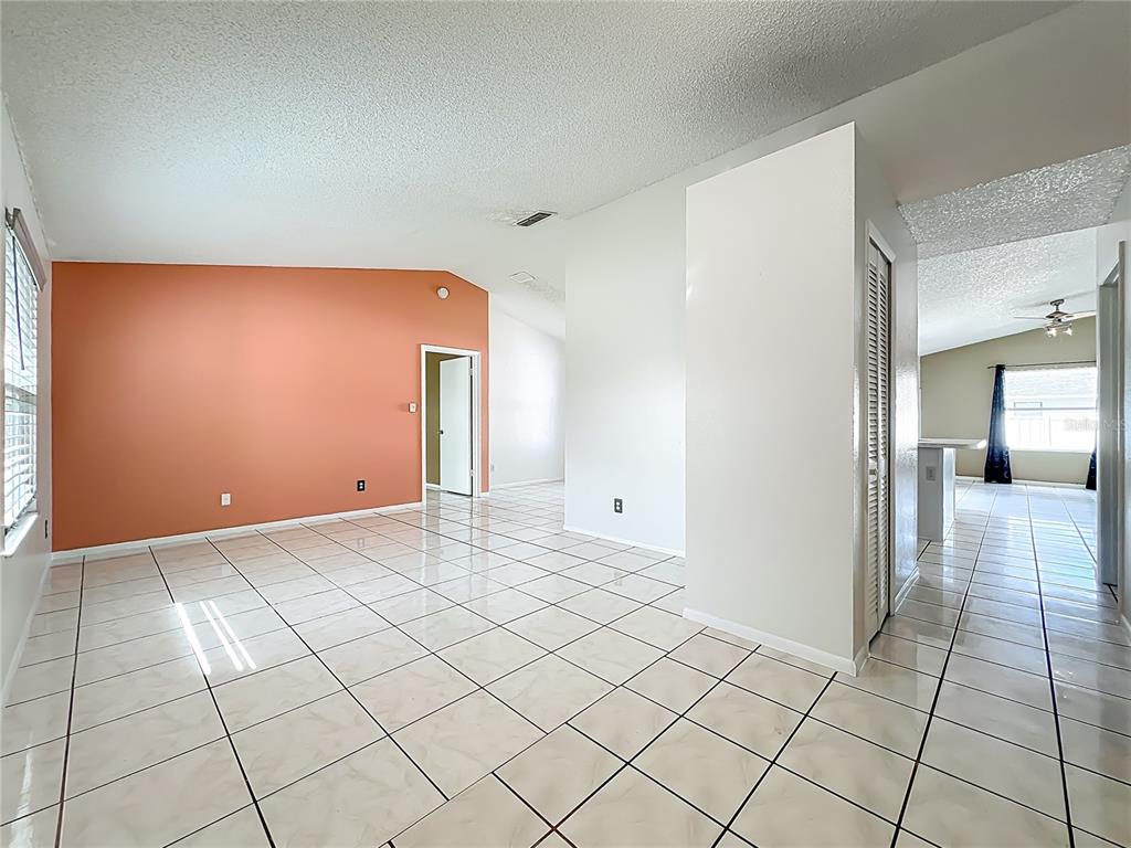A tan front door sits on a concrete porch next to a landscaped garden bed — 6449 ROYAL TERN STREET, ORLANDO, FL