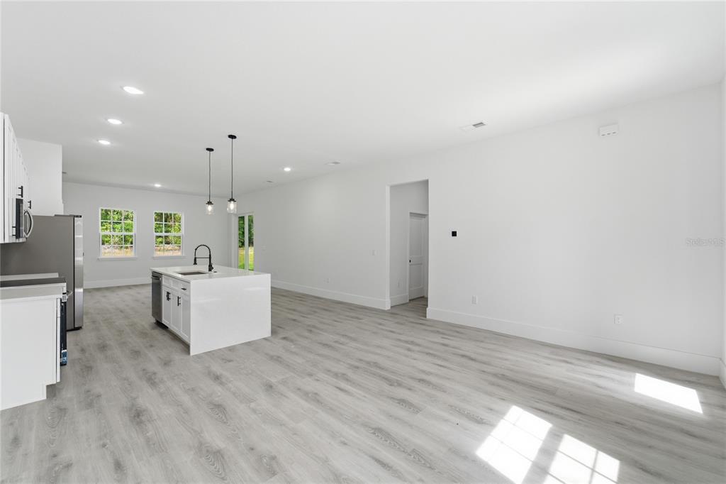 A modern kitchen with a white island and light wood-look flooring in an open room — 238 E CALDWELL DRIVE, DUNNELLON, FL