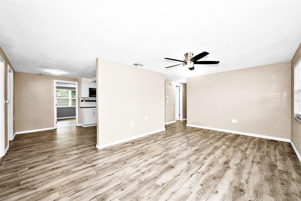 A living room with light-colored walls, wood-look flooring, and a ceiling fan — 10910 BRIDLETON ROAD, PORT RICHEY, FL