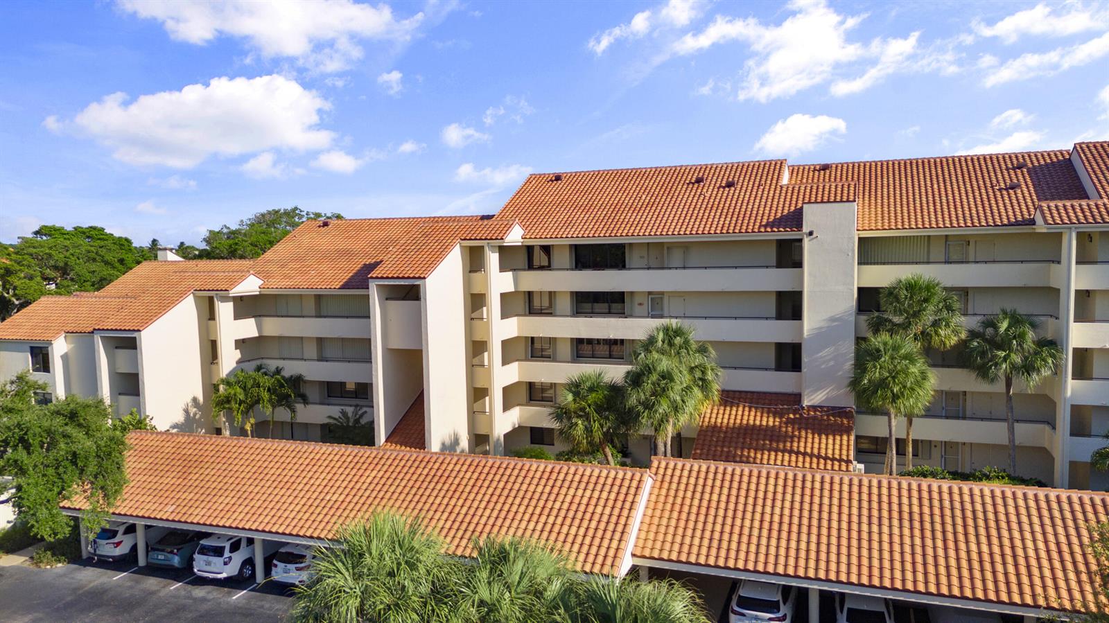 An exterior view of a multi-story apartment building with a tiled roof and covered parking — 1000 N Us Highway 1, Jupiter FL 33477, JUPITER, FL