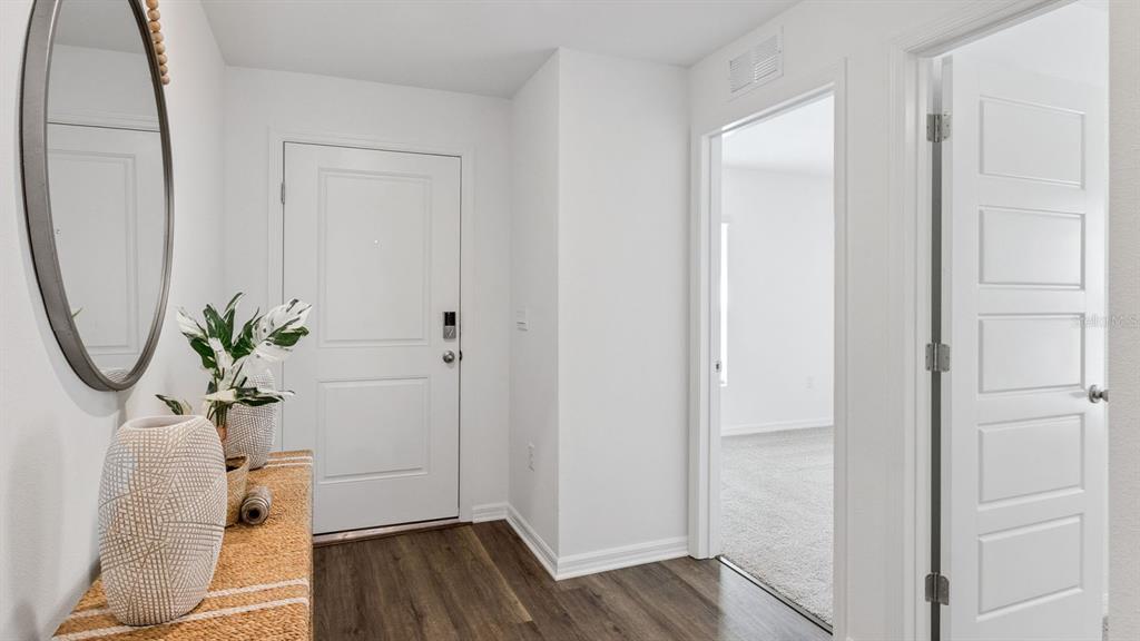 An entryway features a white door, a textured console table, a mirror, and wood flooring — 1731 GRANDIOSE DRIVE, HAINES CITY, FL