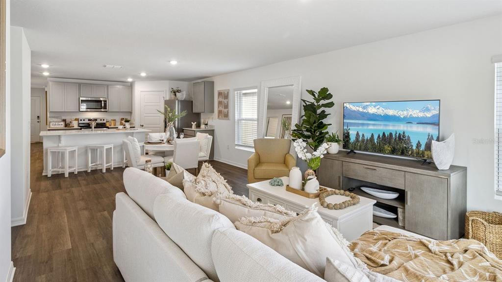 An open-concept living room and kitchen featuring light wood flooring and white cabinetry — 1731 GRANDIOSE DRIVE, HAINES CITY, FL