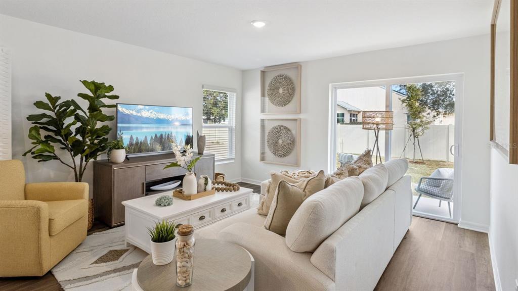 A living room features a beige sofa, yellow armchair, white coffee table, and sliding glass doors — 1731 GRANDIOSE DRIVE, HAINES CITY, FL